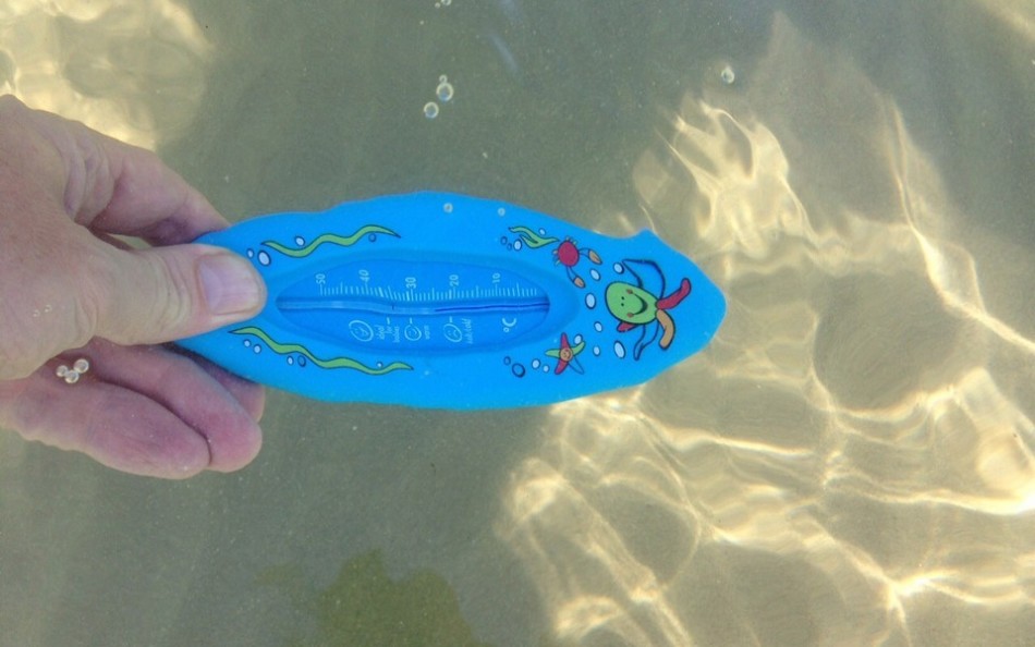 Мужчина окунул термометр в воду красного моря для определения ее температуры